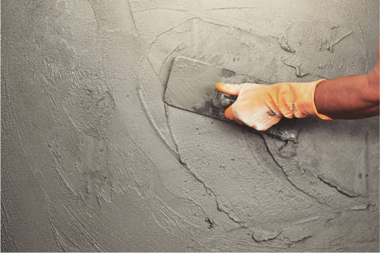worker using a handtool to spread/flatten concrete